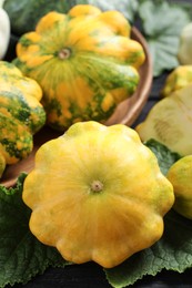 Fresh ripe yellow pattypan squashes with leaves on table, closeup