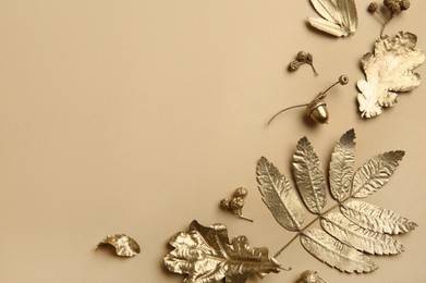 Beautiful golden leaves, berries and acorns on beige background, flat lay with space for text. Autumn decor