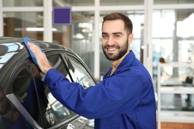 Photo of Portrait of worker cleaning automobile with rag at car wash