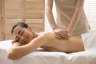 Photo of Woman receiving back massage on couch in spa salon