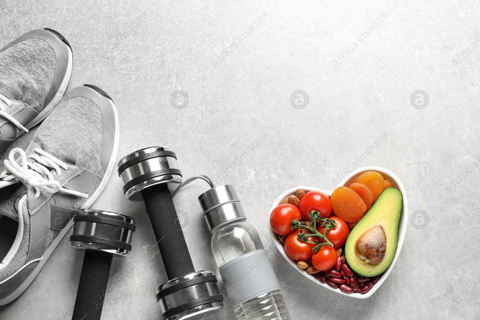 Photo of Heart-healthy products and sports equipment on grey background, flat lay. Space for text