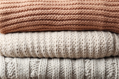 Photo of Stack of folded warm knitted sweaters, closeup