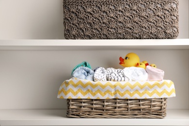 Photo of Basket with clothes for baby on shelf