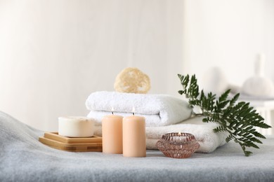 Spa composition. Burning candles, soap, towels and loofah on soft grey surface