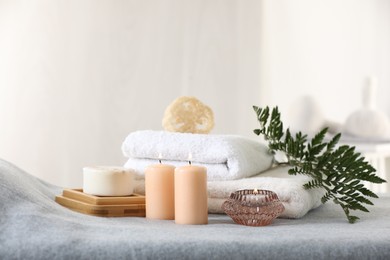 Photo of Spa composition. Burning candles, soap, towels and loofah on soft grey surface