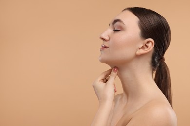 Beautiful woman touching her chin on beige background. Space for text