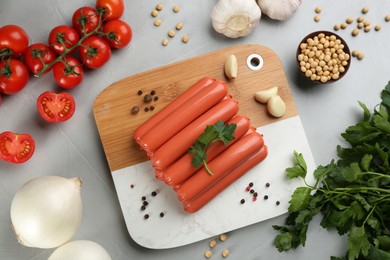 Photo of Fresh raw vegetarian sausages and vegetables on grey table, flat lay