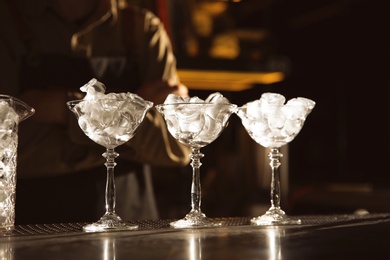 Photo of Martini glasses with ice cubes on bar counter