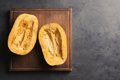 Wooden board with cut spaghetti squash on gray background, top view. Space for text