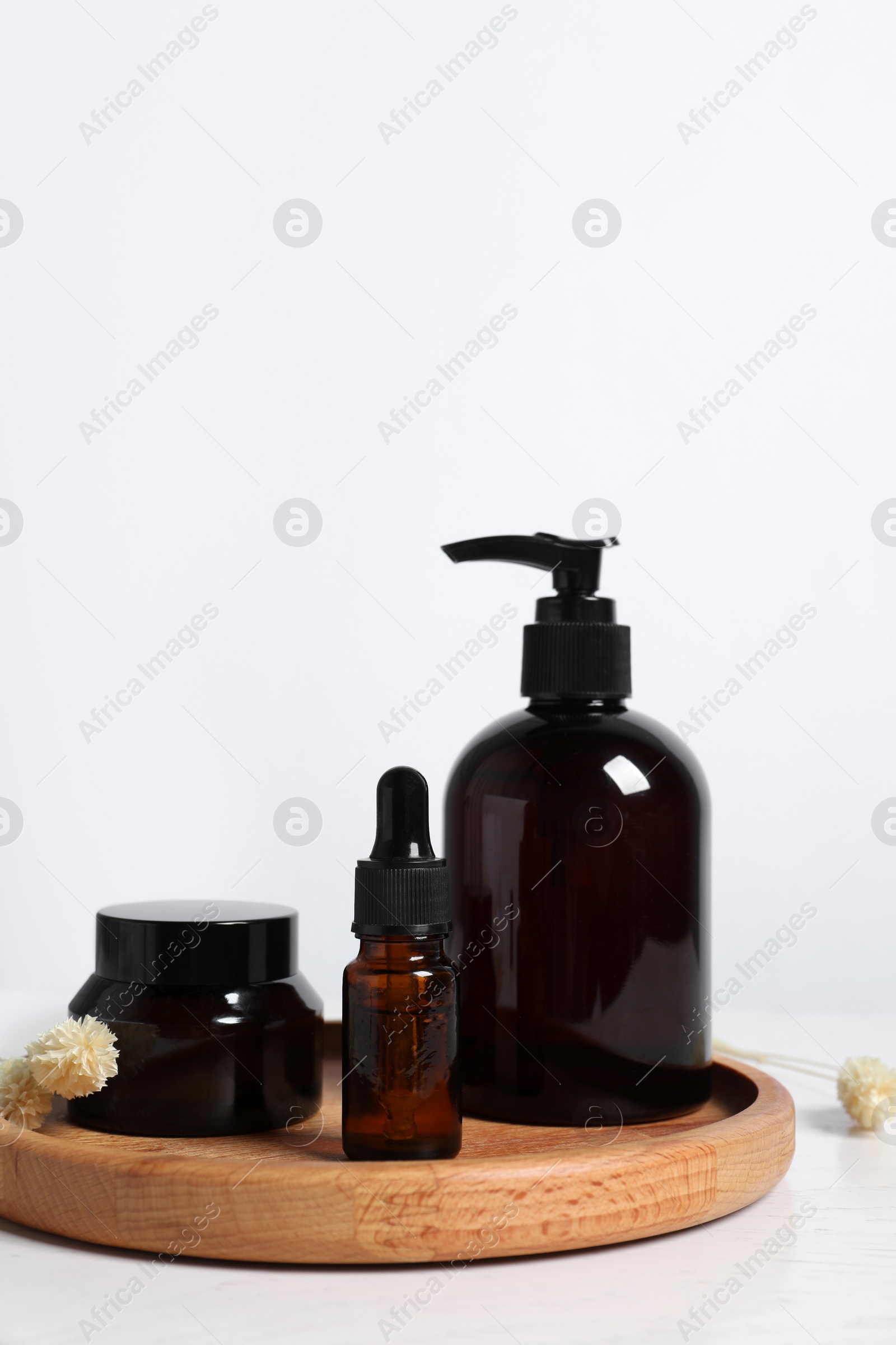 Photo of Different cosmetic products and dry spikes on white wooden table