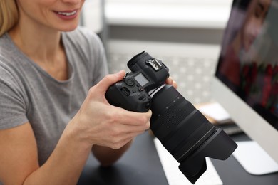 Photo of Professional photographer with digital camera at table indoors, closeup