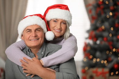 Happy mature couple in Santa hats at home. Christmas celebration