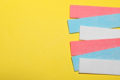 Photo of Sticks of tasty chewing gum on yellow background, flat lay. Space for text