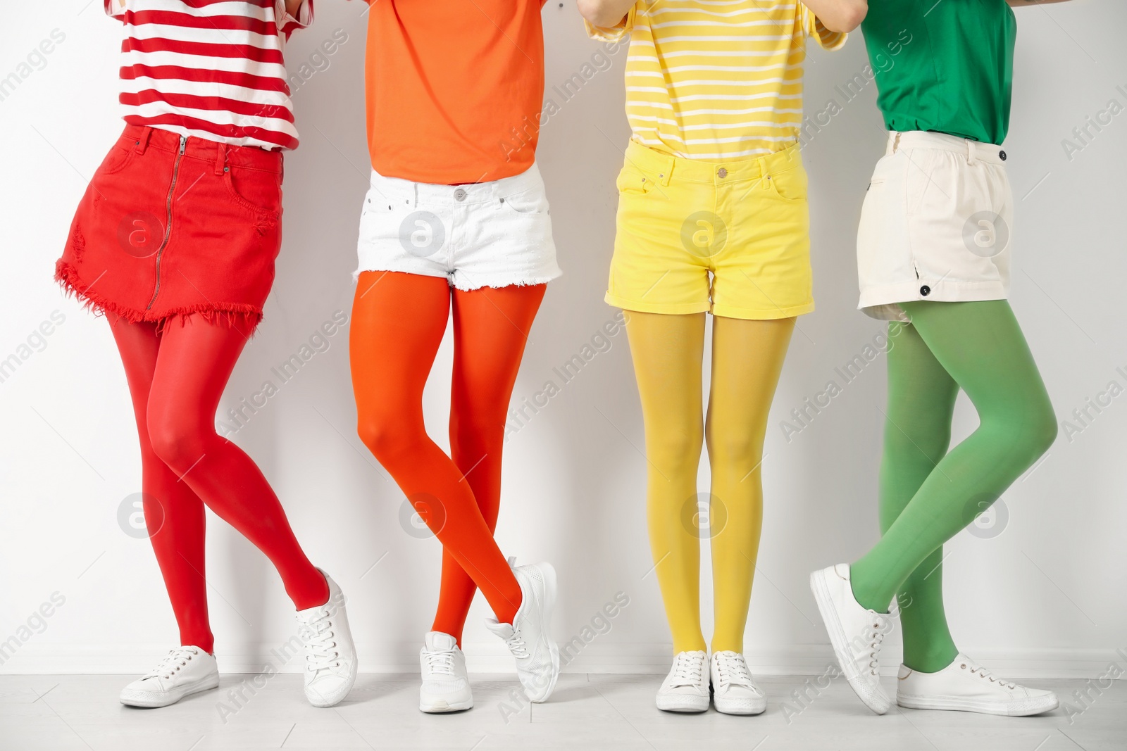 Photo of Women wearing bright tights near white wall, closeup