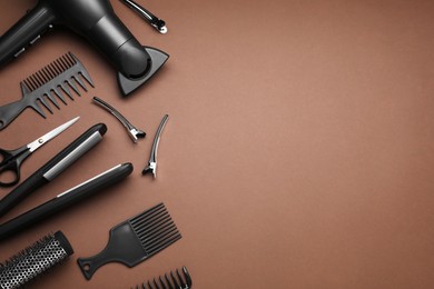 Photo of Flat lay composition of professional hairdresser tools on brown background, space for text