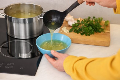 Photo of Man pouring delicious soup into bowl in kitchen, closeup