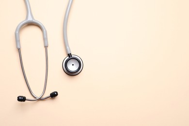 Stethoscope on beige background, top view. Space for text