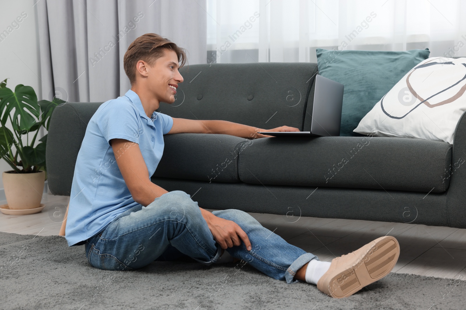 Photo of Happy young man having video chat via laptop on sofa indoors