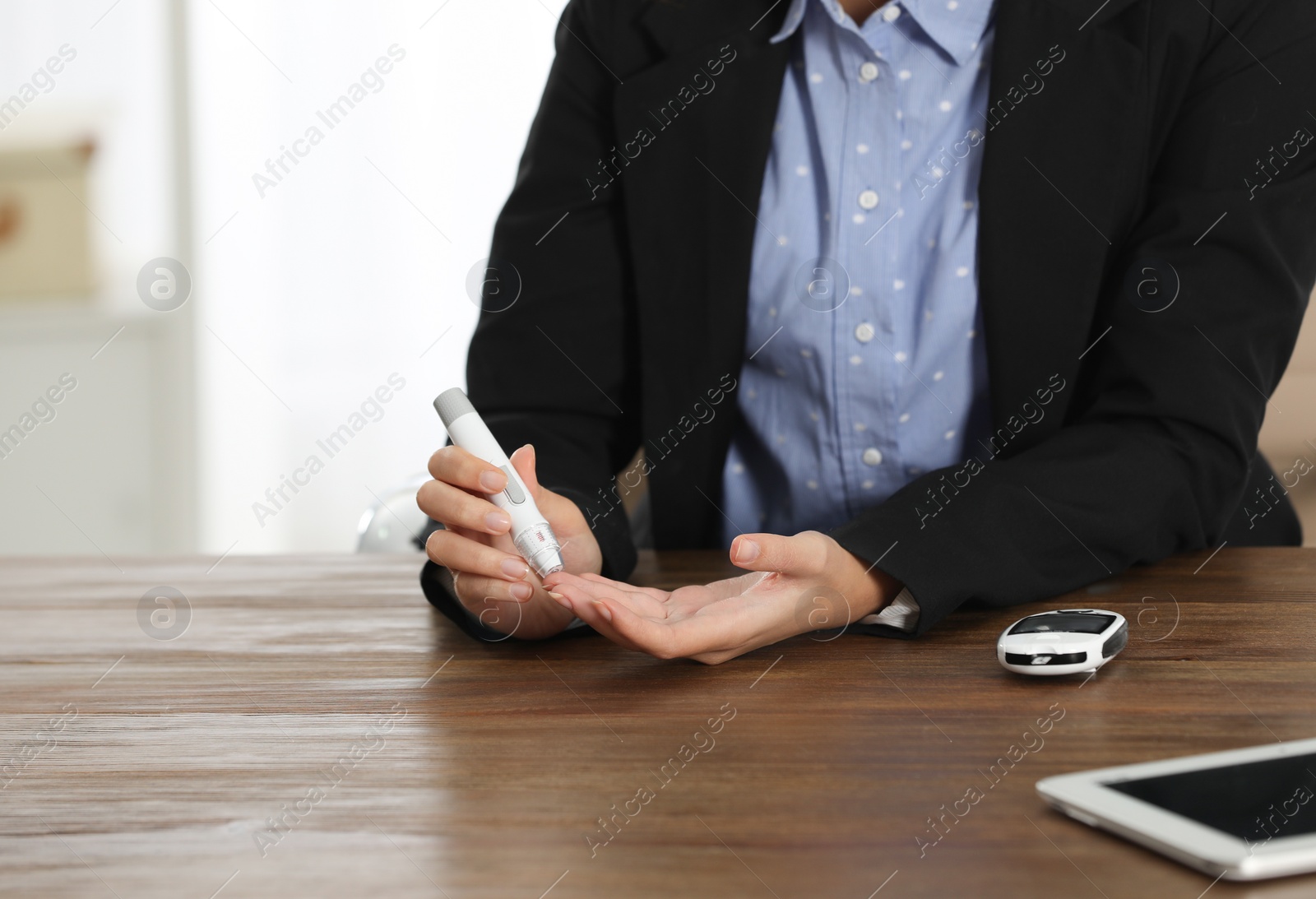 Photo of Young African-American woman using lancet pen at workplace, closeup. Diabetes control