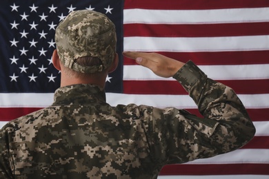 Photo of Soldier in uniform against United states of America flag, back view