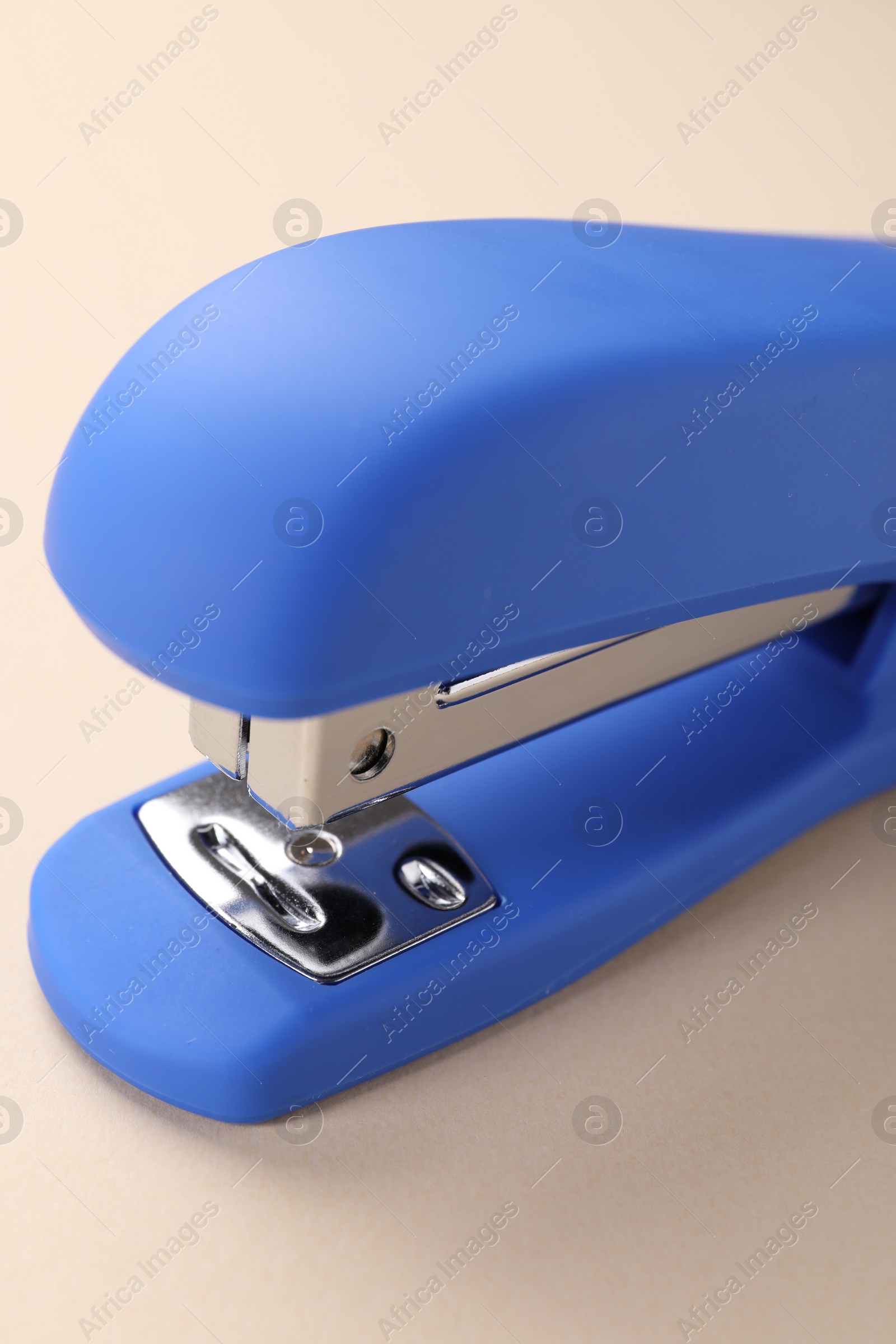 Photo of One blue stapler on beige background, closeup