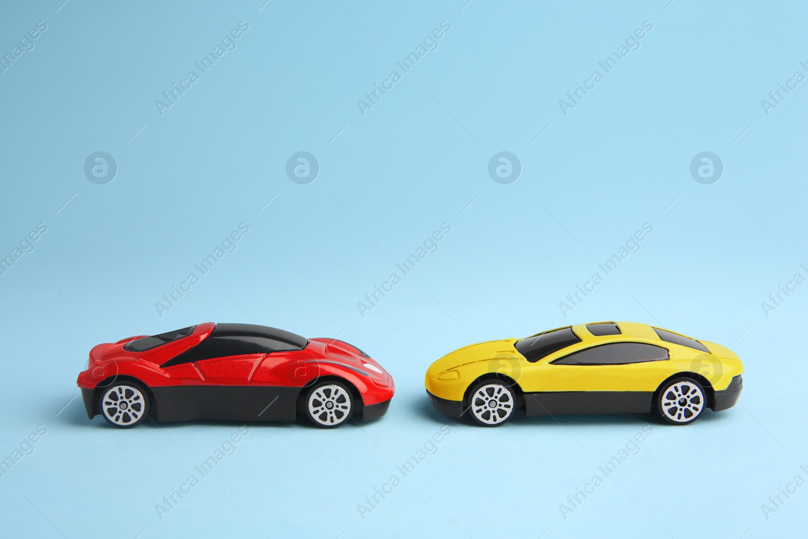 Photo of Two bright cars on light blue background. Children`s toys