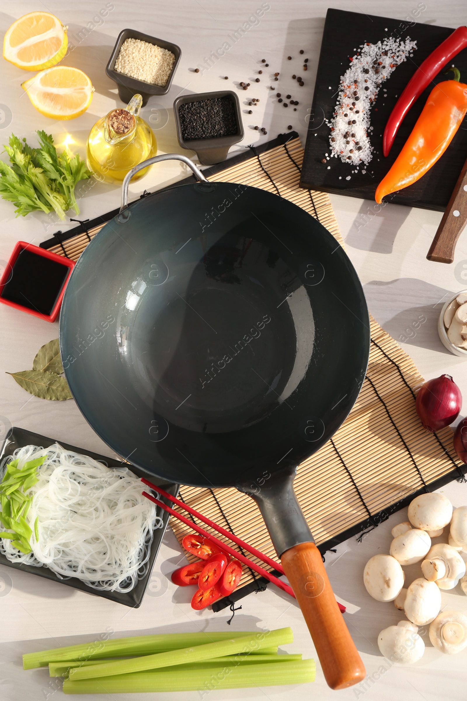 Photo of Wok, chopsticks and different products on white wooden table, flat lay