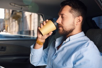 Photo of To-go drink. Handsome man drinking coffee in car, space for text