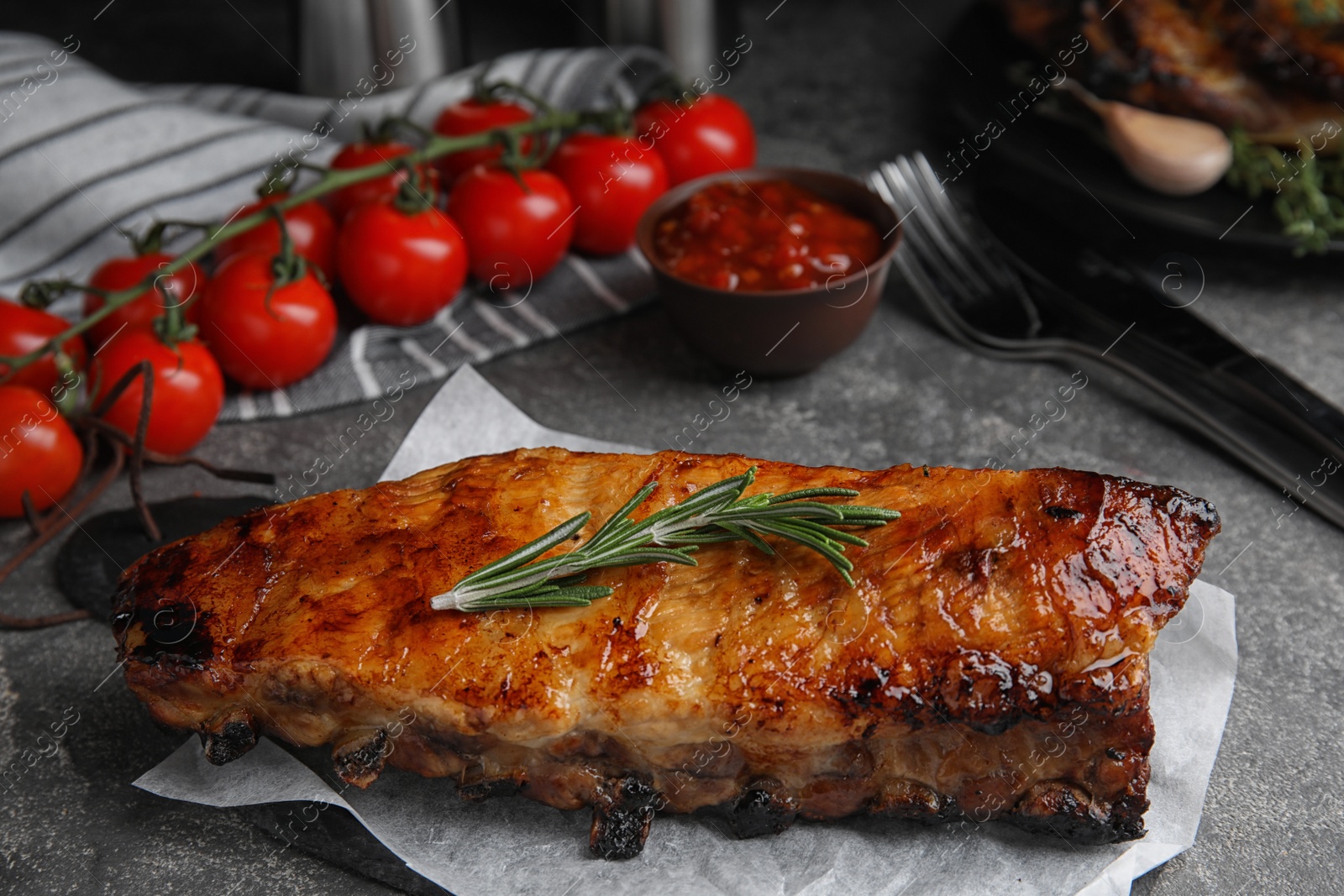 Photo of Tasty grilled ribs with rosemary on grey table