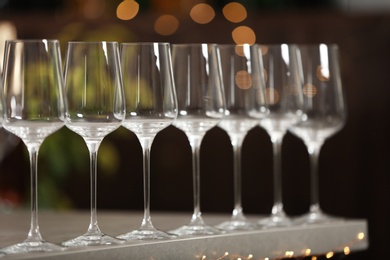 Photo of Set of empty wine glasses on grey table against blurred background