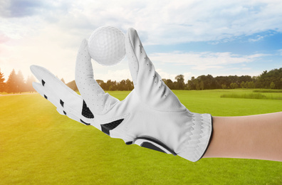 Image of Player holding golf ball in park on sunny day, closeup