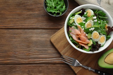 Photo of Delicious salad with boiled eggs, salmon and cheese served on wooden table, flat lay. Space for text