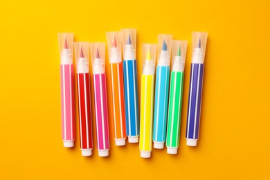 Photo of Many bright markers on yellow background, flat lay