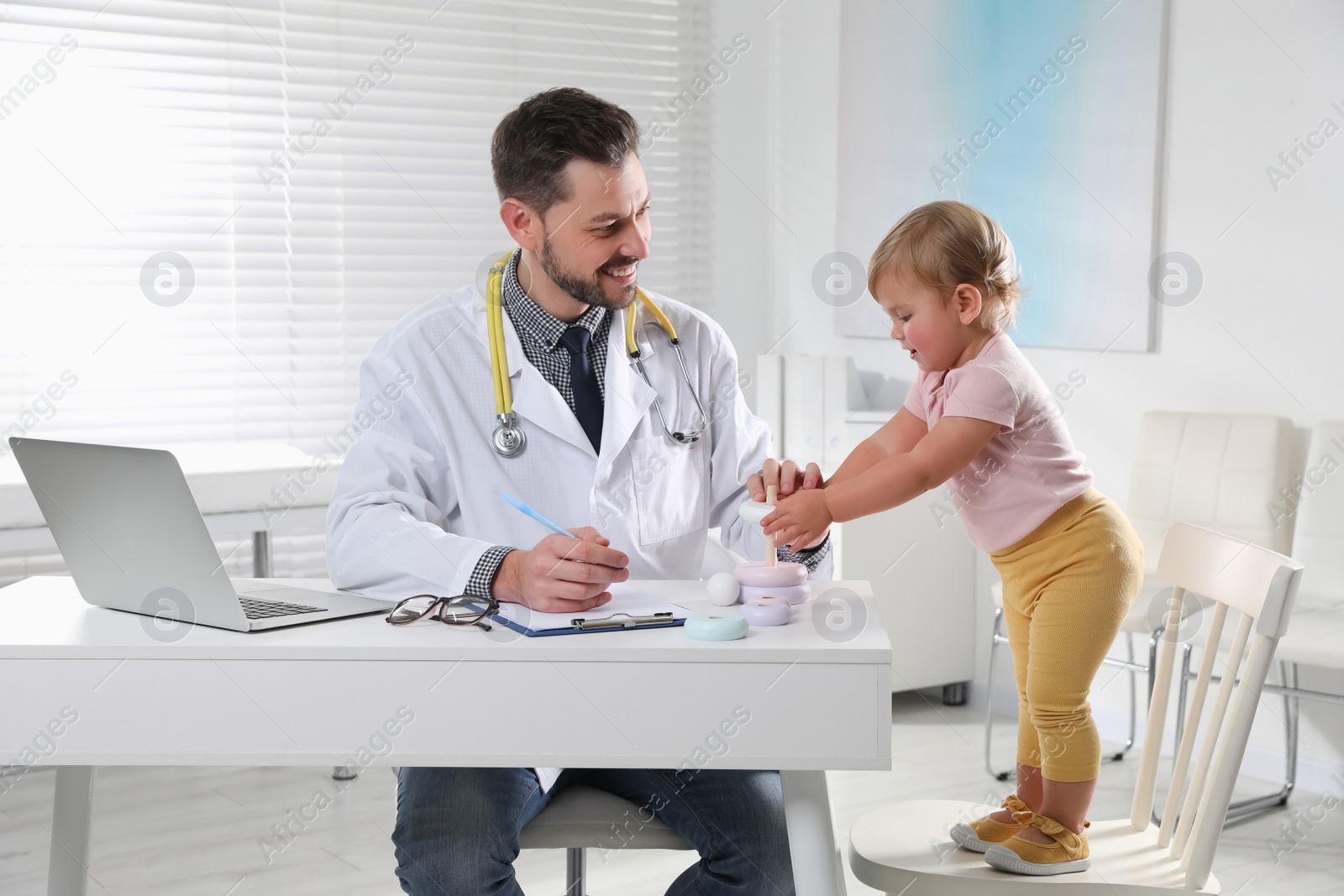 Photo of Pediatrician playing with cute baby in clinic