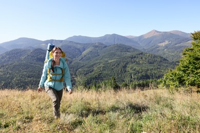 Photo of Tourist with backpack walking in mountains on sunny day