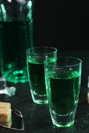 Photo of Absinthe in shot glasses on gray table, closeup. Alcoholic drink