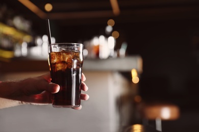 Photo of Man holding glass of refreshing cola indoors, closeup. Space for text