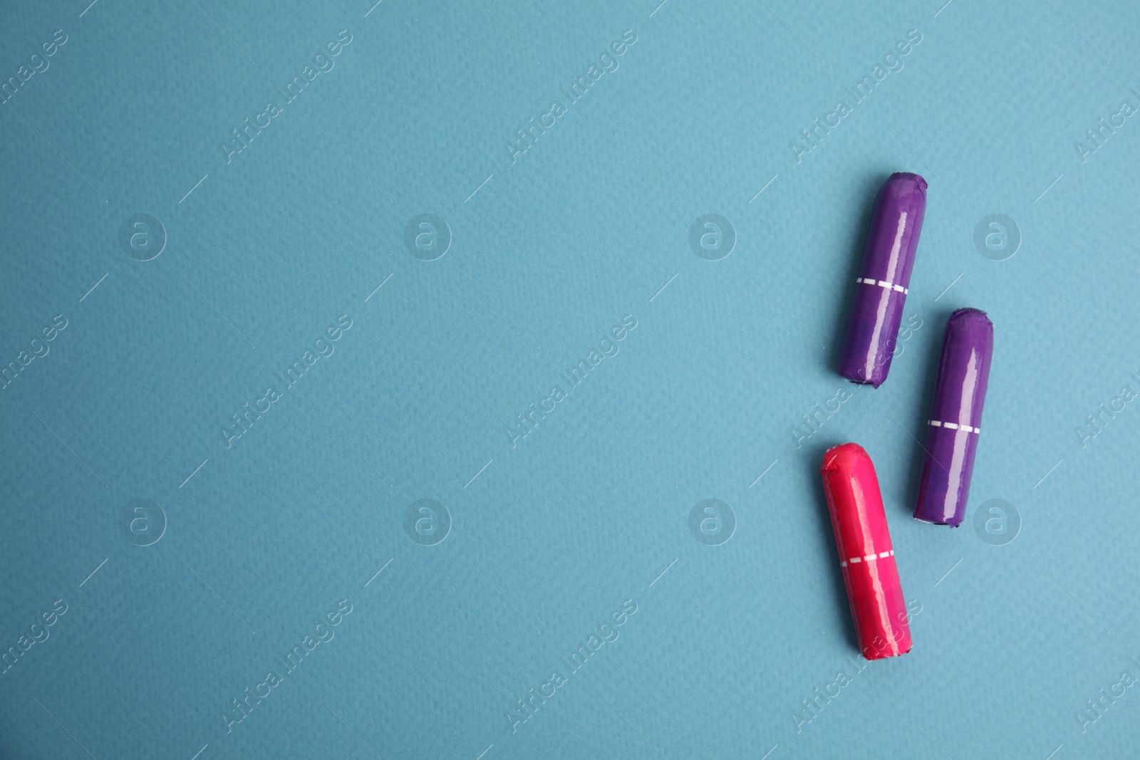 Photo of Colorful tampons on blue background, flat lay. Space for text