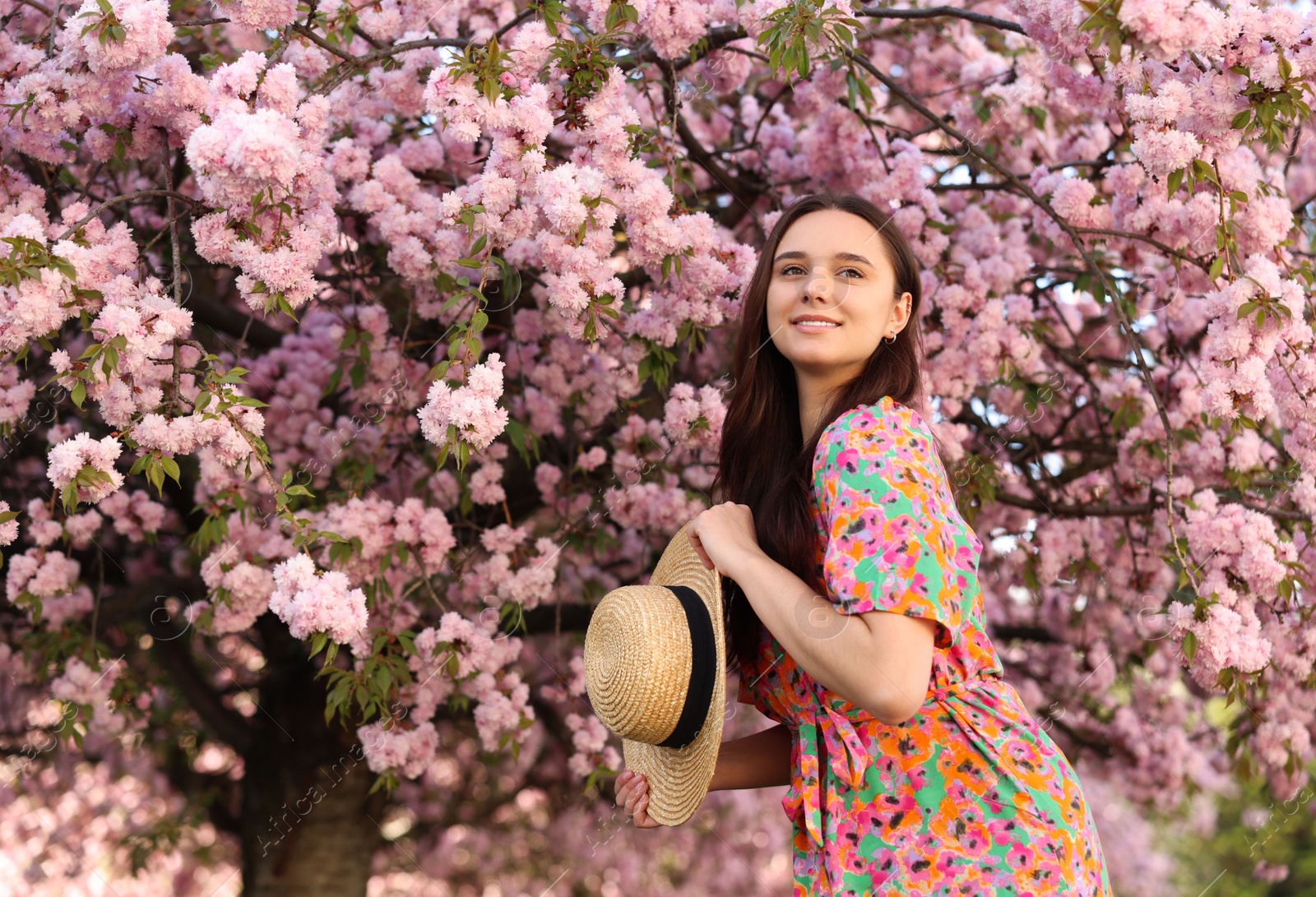 Photo of Beautiful woman with straw hat near blossoming tree on spring day