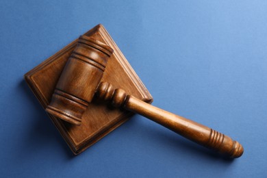 Photo of Wooden gavel and sound block on blue table, top view