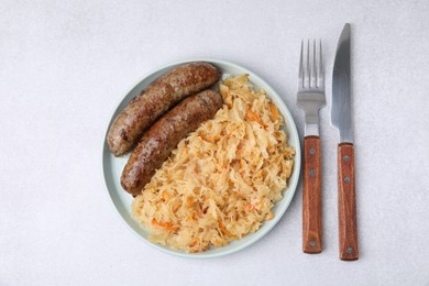 Photo of Plate with sauerkraut and sausages on light table, flat lay