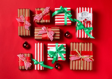 Photo of Christmas gift boxes on red background, flat lay