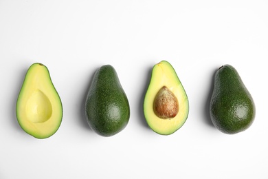 Cut and whole fresh ripe avocados on white background, top view