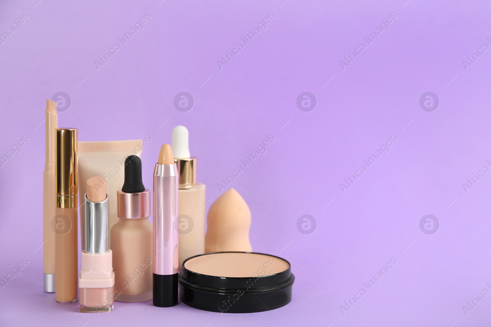Photo of Foundation makeup products on violet background, space for text. Decorative cosmetics
