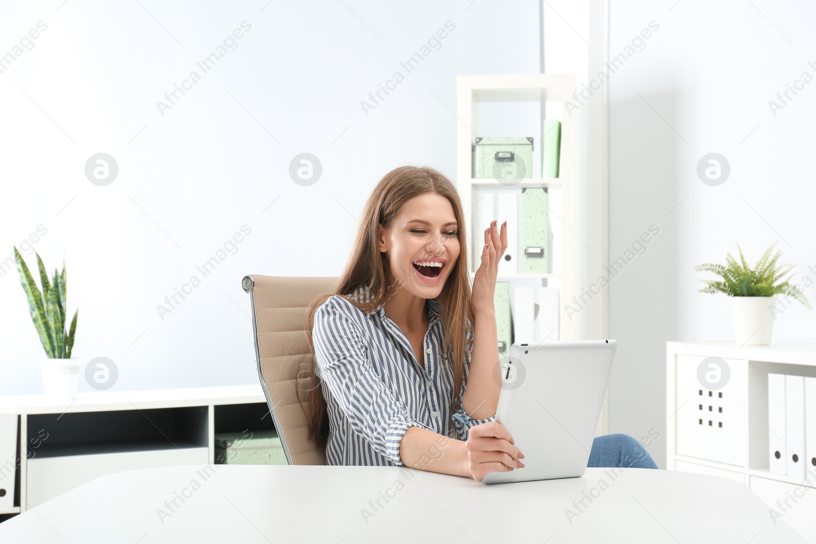 Photo of Emotional young woman with tablet celebrating victory in office