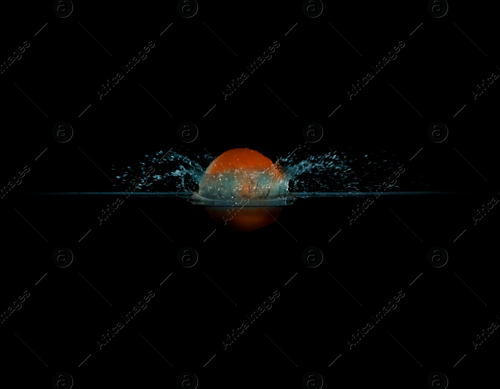 Photo of Tangerine falling down into clear water against black background