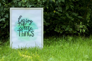 Photo of Poster with phrase Enjoy The Little Things on grass outdoors, space for text
