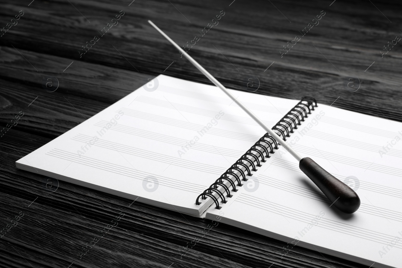 Photo of Conductor's baton and lead sheet on black wooden table