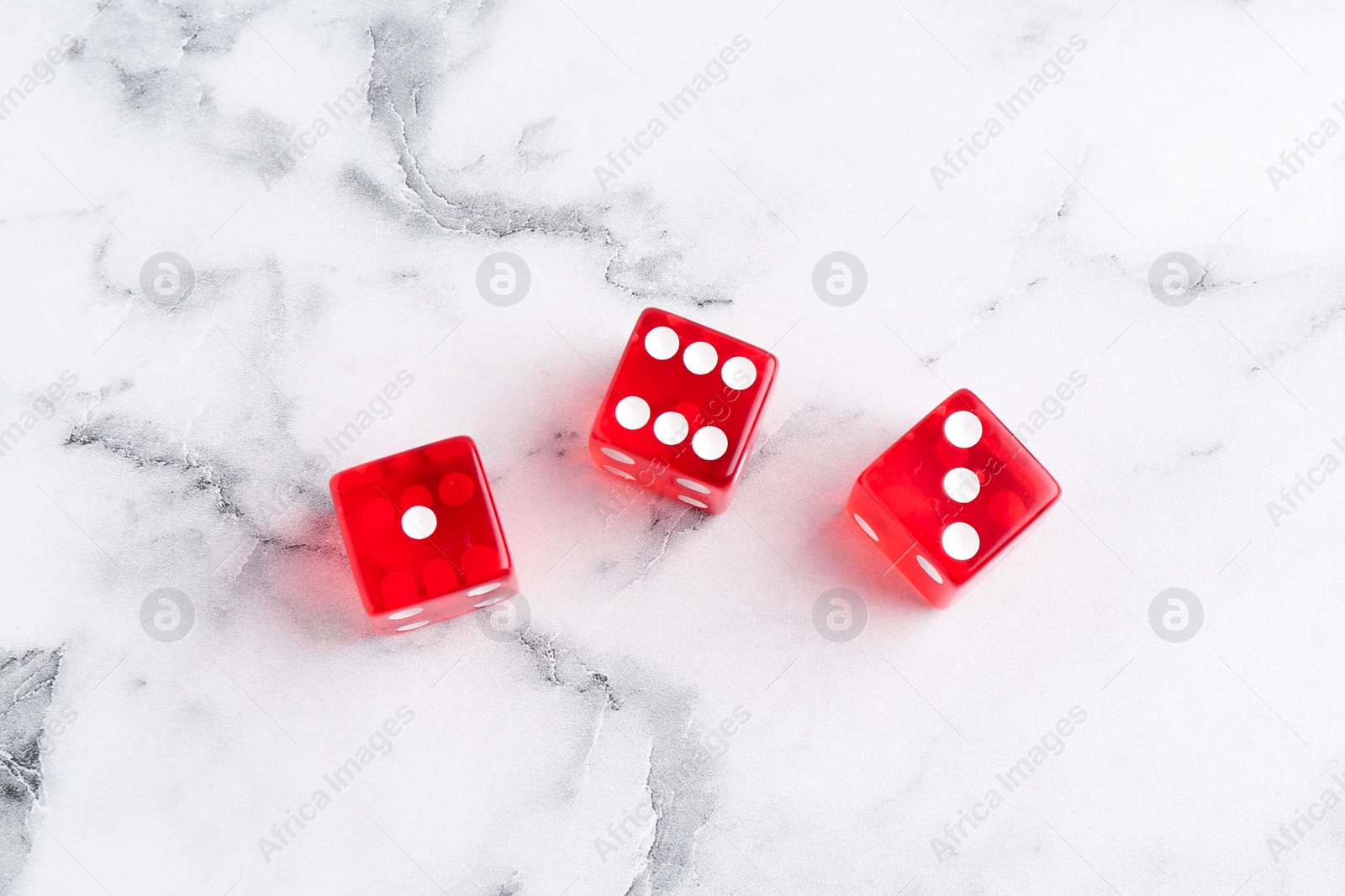 Photo of Three red game dices on white marble table, flat lay