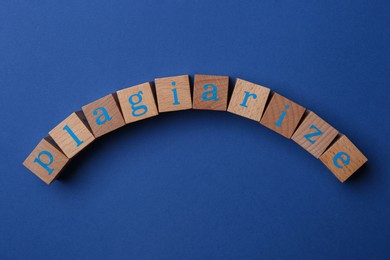 Photo of Word Plagiarize made of wooden cubes with letters on blue background, top view